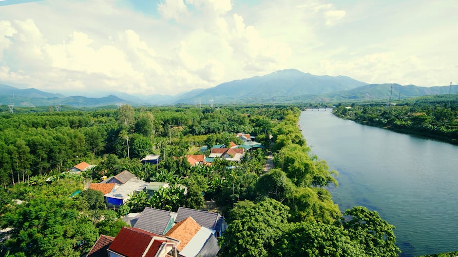 Aerial view of a tranquil river valley surrounded by lush greenery and scattered houses.